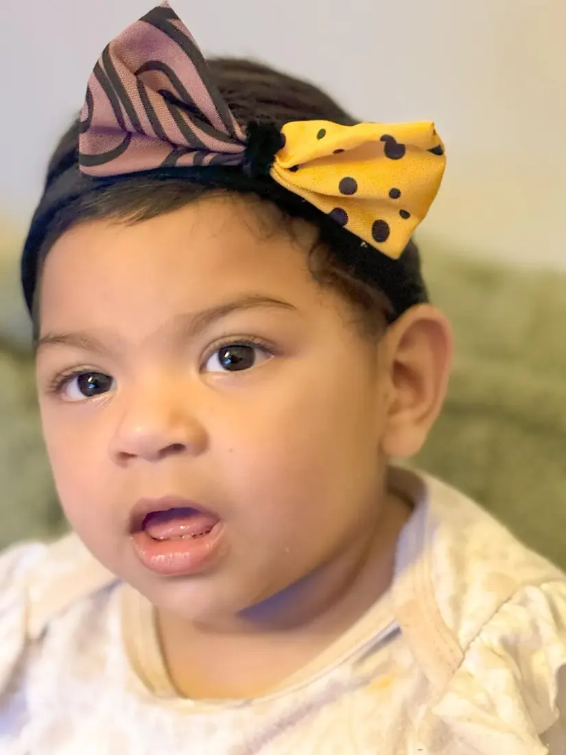 A child wearing a two-tone bow headband in a warm portrait