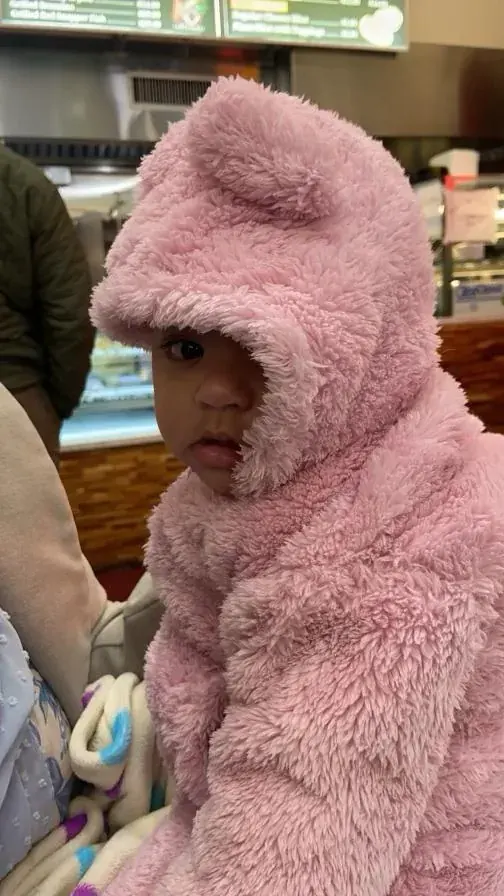 A child bundled in a soft pink hooded coat